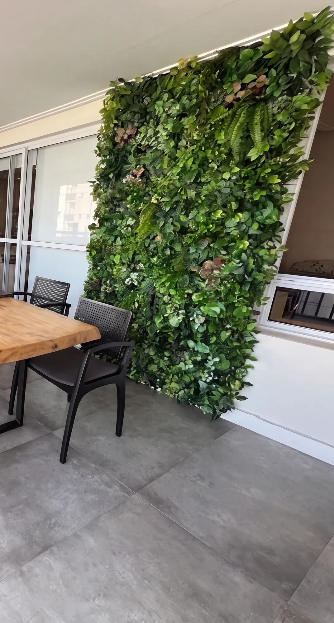 Jardim vertical em painel de altura inteira na ponta da varanda.